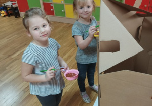 zadowolone dziewczynki malują ściany domku z piernika